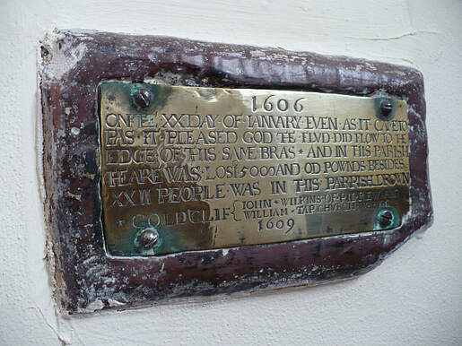 A plaque with a brass plate attached and an inscription