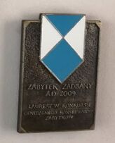 Enamel blue and white shield on a small bronze plaque with writing in Polish on it