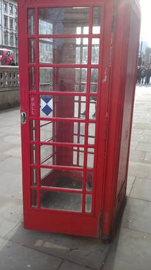 Red telephone box with a small blue shield sticker in the middle of one window