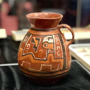 A red and orange pottery jug on a table