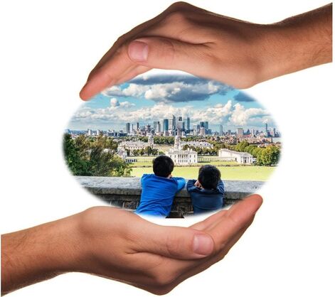 two hands with a photo in them showing two children looking over a green space with a city in the background